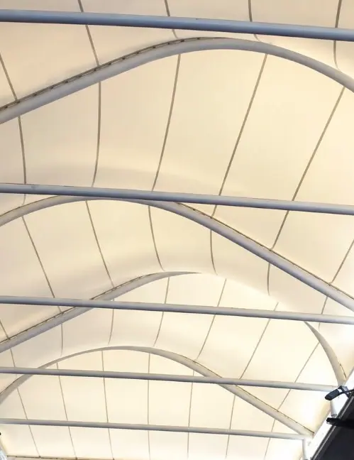 Corredor cubierto con arcos metálicos y membrana blanca
